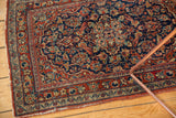 Fine Kashan rug's cherry red and navy scrolling floral border showing wear and exposed foundation.