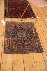 Persian Kashan rug corner: navy blue floral field, cherry red borders, threadbare outer stripe.