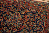 Kashan rug close-up: threadbare red outer border, exposed foundation, and navy floral motifs.