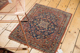 Traditional Persian Kashan rug corner with intricate floral motifs and textured, worn edge.