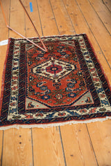 Corner of vintage Engelas rug showcasing brick red Herati field and light tattered ivory fringe.