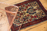 Vintage American Sarouk rug corner: low pile, ivory ground, navy border, and tattered edge.