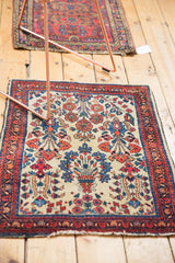 Vintage Sarouk rug's low pile with cherry red, blue florals, and tattered fringe.