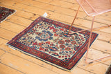 Corner of vintage Sarouk rug, low pile ivory field, blue-red floral design, and tattered end.