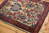 Vintage American Sarouk rug corner with low pile, tattered end, and intricate floral border.