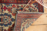 Ivory ground with tree-of-life motif on vintage American Sarouk rug corner, showing tattered fringe.