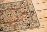 Tattered corner of antique Haji Jalili Tabriz rug, dusty rust, ivory, and navy serpent border.
