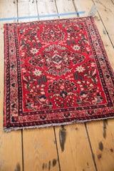 Cherry red floral field of a vintage Sarouk rug, with navy blue border and ivory fringe.