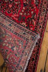 Hand-knotted construction on reverse of cherry red floral Sarouk rug, with fringe.