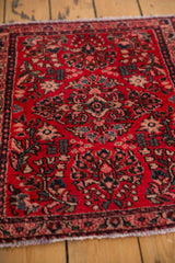 Vintage Sarouk rug corner, featuring cherry red floral patterns and secured fringe.