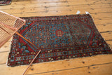 Vintage Malayer rug corner, showing intricate wine red border and aqua blue Herati field.