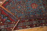 Detail of vintage Malayer rug: Aqua blue Herati field, red and beige geometric borders, visible wear.