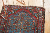 Malayer rug corner with aqua blue Herati motif, ruby red border, and tattered ends.