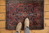 Vintage Sarouk rug's central medallion with blossomed floral cross-sections in brick red and navy.