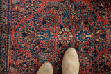 Vintage Sarouk rug's intricate floral palmettes in brick red, navy, and teal, underfoot.