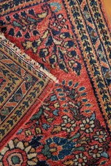 Vintage Sarouk rug corner with brick red floral pile, navy accents, and geometric foundation.