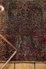 Vintage Sarouk rug close-up: central potted tree of life with raspberry and navy blossoms.