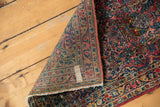 Folded corner of the Sarouk rug, revealing its hand-knotted reverse and intricate floral pile.