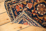 Vintage Borchalou rug corner showing navy, rust, and beige intricate border with light tatter.