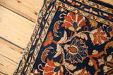 Tattered side of Borchalou rug, navy blue field with oversized scrolling botanical design.