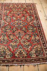 Vintage Sarouk runner's floral pattern, ornate border, and light tatter to end fringe.