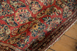 Close-up of vintage Sarouk rug's cherry red field with navy and sand floral patterns.