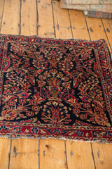 Dark navy Sarouk rug features central tree of life, red florals, low pile, and tattered ends.