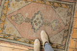 Close-up of Vintage Oushak rug: dusty peach elongated medallion with rams horn finials and worn pile.