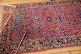 Angled view of a vintage Sarouk rug showing blossoming plants and navy floral border.