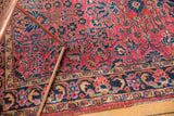 Vintage Persian Sarouk rug border showing aged raspberry red field and deep navy floral motifs.