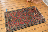 Vintage Dargezine rug corner, showing blush field, navy floral border, and light tatter to fringe.
