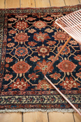 Lower border of vintage Lilihan rug, navy Veramin pattern, red florals, fringe, and white knots.