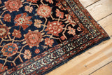 Lilihan rug corner: navy field, madder red Veramin florals, white knots, worn edge.