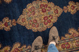 Hand-knotted Kerman rug, displaying Rococo-style roses on a dark blue field, with feet.