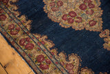 Vintage Kerman rug corner, deep indigo field, Rococo rose border, and visible sprouted white knots.