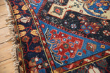 Vintage Malayer rug with intricate navy border, saffron motifs, red accents, and geometric field.