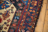 Vintage Malayer rug detail: ornate navy, ivory patterns, visible varied pile, and worn edge.