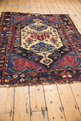 Tattered end and dark blue outer border with floral motifs on a vintage Malayer rug.