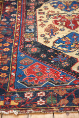 Vintage Malayer rug section: rich indigo, red, and ivory patterns; visible foundation, tattered fringe.