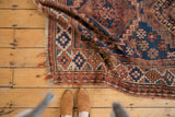 Geometric navy, madder red, ivory motifs with tattered fringe on vintage Caucasian rug.