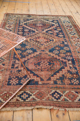 Close-up view of vintage Caucasian rug with tattered fringe and geometric border.