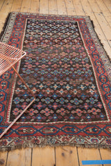 Kurdish rug's geometric medallions in madder red, teal, and ivory, revealing foundation wear.