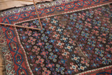 Antique Kurdish rug detail: red, blue, charcoal geometric medallions with authentic pile wear.