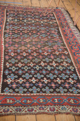 Antique Kurdish rug detail: staggered geometric medallions in madder red, teal, ivory, showing wear.