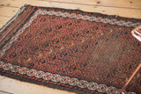 Antique Belouch rug runner showing geometric lattice, germinating flowers, chestnut brown, and border tatter.
