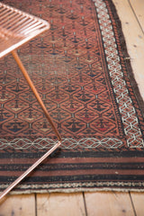 Tattered fringe and striped charcoal brown end border of an antique Belouch runner.