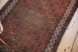 Geometric diamond border and frayed edge along the side of an antique Belouch runner.