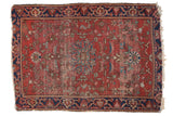 Antique Farahan Sarouk rug: dusty cherry red field, central floral medallion, intricate vines, and visible patina.