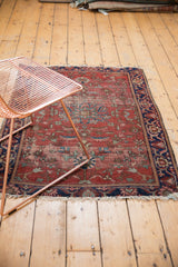 Hard tattered end and navy border with blush, teal floral patterns on an antique Farahan Sarouk rug.