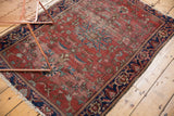 Antique Farahan Sarouk rug with prominent tattered end, deep navy border, and aged cherry red field.